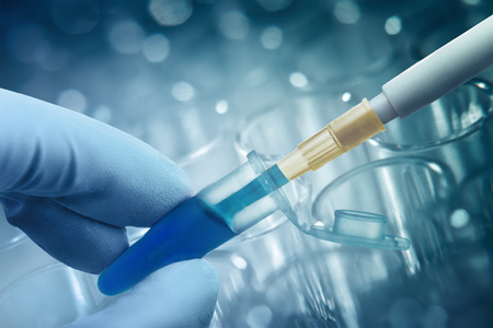 Hand in glove keeps plastic tube with dipped pipette, plastic plate for immunosorbent assay on backgroundの写真素材