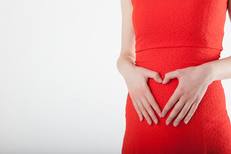 Pregnant young woman with heart sign made from handsの写真素材