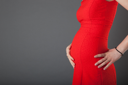Pregnant woman showing her belly at studioの写真素材