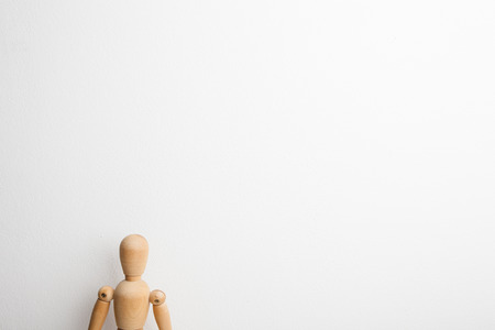 Wooden dummy posing in front of the white wallの写真素材