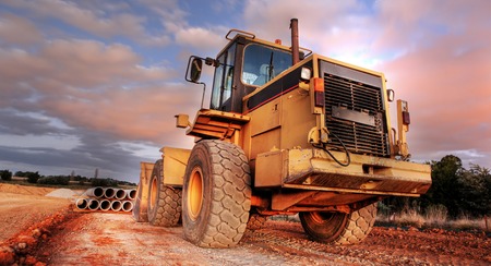 Backhoe loader or bulldozer - excavator during sunset