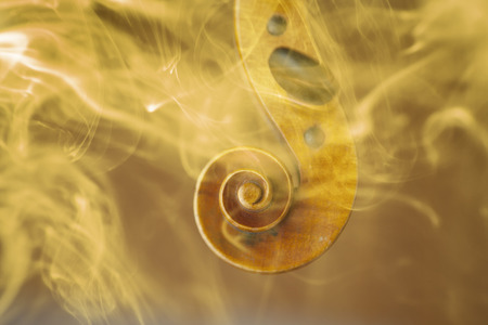 Old violin head surrended with colored smoke and flames - music conceptの写真素材