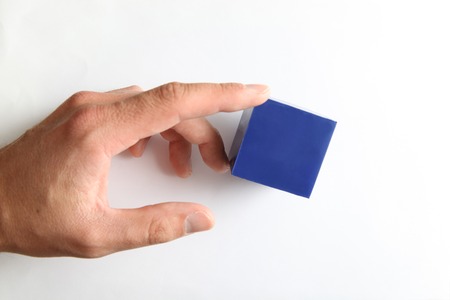 Hand touching small blue cube isolated on white background. Business concept.の写真素材