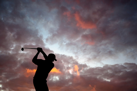 Golfer playing golf during beautiful sunset at competition eventの写真素材