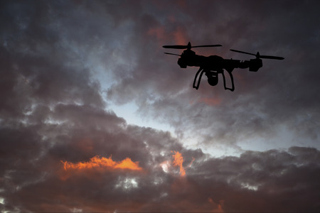 Innovation concept. Silhouette of drone flying on sunset. Heavy lift drone photographing at sunset.の写真素材