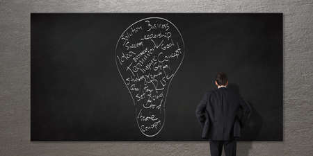 Businessman standing in front of chalkboard. Bulb idea creative concept. Vision and strategy business conceptの写真素材