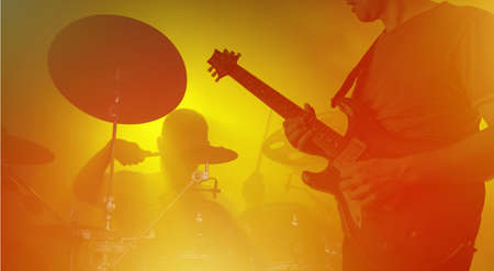 Band performing live during concert, gig. Guitarist and drummer silhouettes
