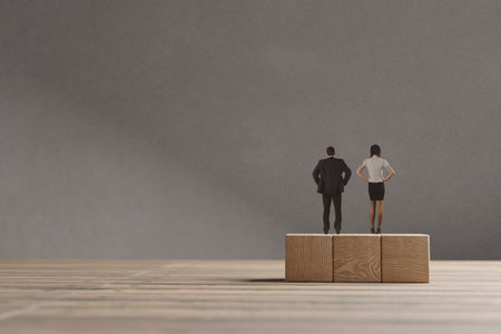 Miniature man and woman standing on the wooden blocks. The concept of the equal opportunities for genders.の写真素材