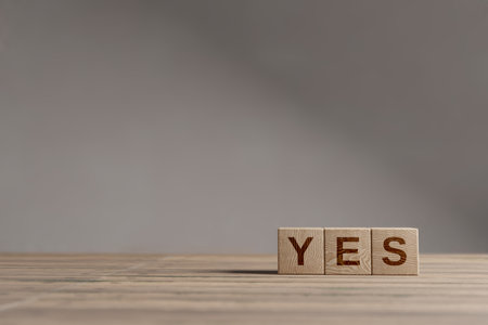 Wood cubes with acronym 'YES' on a beautiful wooden table, studio background. Business concept with copy space.の写真素材