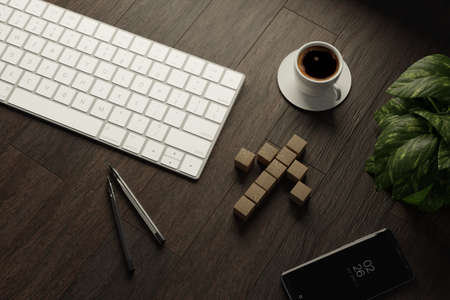 Work from home. desk office with keyboard, blank wooden cubes in arrow, coffee cup and pen on wood table. Flat lay top viewの写真素材