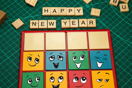 Happy new year text on wooden cubes with smiley face on green backgroundの写真素材