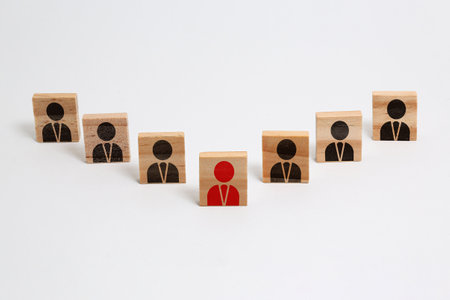 Selective focus on stacked wooden pieces with drawn icons of people on a white background.の写真素材