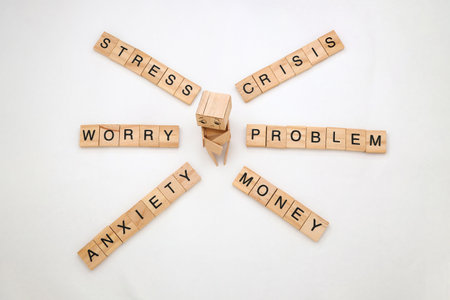 Wooden letter tiles spelling out words associated with financial and emotional distress.の写真素材