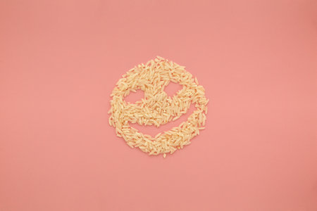 Creative food concept photo of smiley face made of rice on pink background.の写真素材
