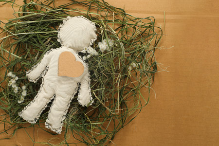 Handmade crochet doll with heart symbol on green grass.の写真素材