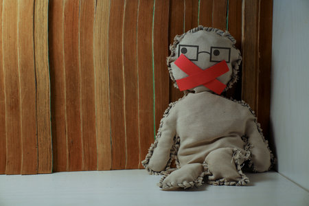 A doll with a red ribbon in her mouth on a book backgroundの写真素材