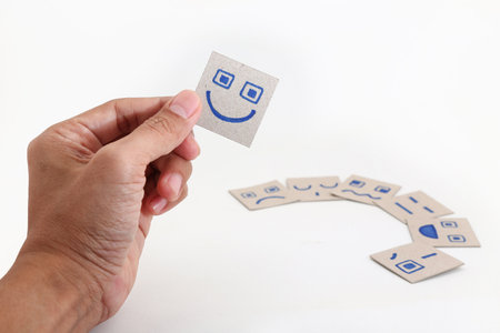 Hand holding a card with smiley face on the white background.