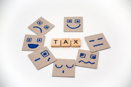 The word TAX on wooden cubes with various emoji faces on squared hard paper.の写真素材