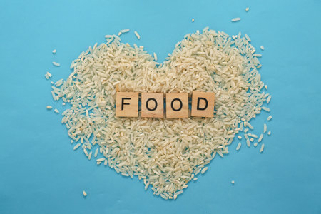 White rice grains form a heart shape on a vibrant blue background, with the word "FOOD" displayed in the center.の写真素材