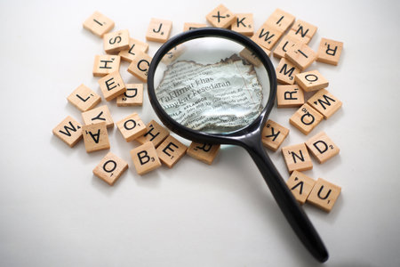 magnifying glass over pieces of paper with wooden cubes on white backgroundの写真素材