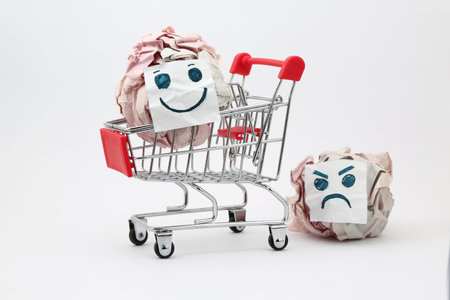 Shopping cart with crumpled paper balls and smiling and angry facesの写真素材