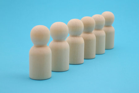 Wooden figures of people stand in a row on a blue background
