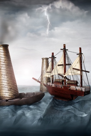 Photo of a miniature ship in an ocean with gray sky behind and a thunderの写真素材