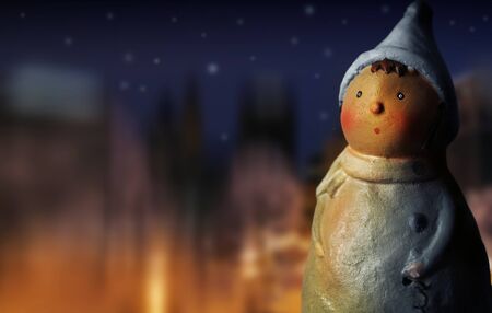 Fantastical photo of a cute handmade figurine in golden fire light against background of night sky and winter lightsの写真素材