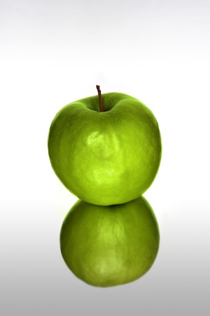 Green apple with reflection against white backgroundの写真素材