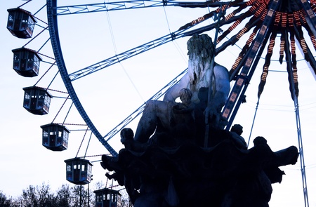 Details of the sculpture fountain representing Neptune in Berlin, with a ferry wheel at the sunset in the backgroundの写真素材