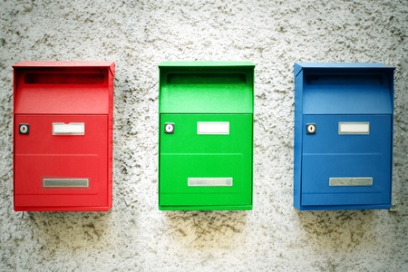 Photo of three colored mailboxes hanging on a wall の写真素材