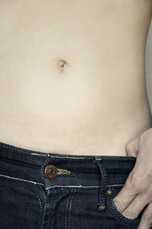 Detail of a belly and jeans dressed by a girl modelの写真素材