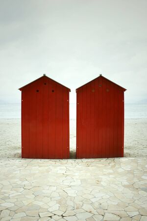 Two red dressing cabins with beach sea and cloudy sky on the backgroundの写真素材