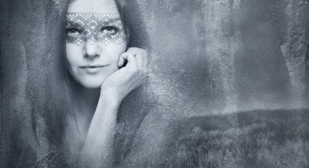 Beautiful seductive young woman face with a eye lace mask in a fantasy dark background
