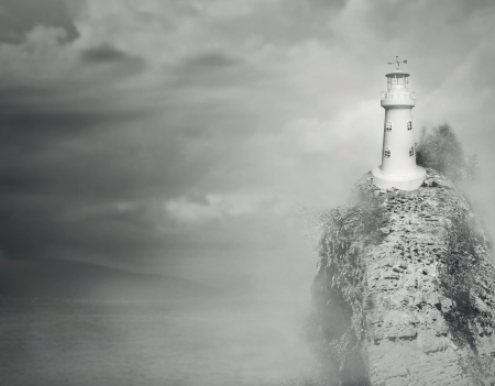 Beautiful fantasy background of a lighthouse on the top of a rocky mountain with sea and cloudy sky in black and whiteの写真素材