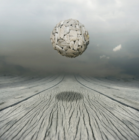 Artistic metaphysical background representing a ball sculpture floating in the air above a wooden floor with the sky on the backgroundの写真素材