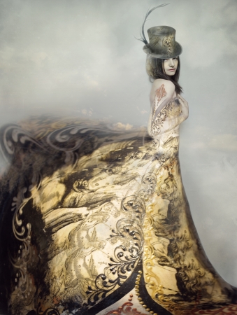 Beautiful artistic portrait of an extravagant lady in an eighteen century style dress and cylinder with clouds in the backgroundの写真素材