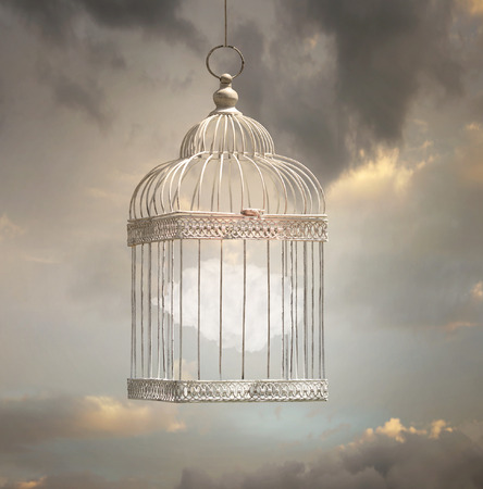 Dreamy image that represent a cloud inside a cage with a beautiful sky in the backgroundの写真素材