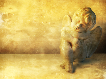A small statue of sweet little angel sitting resting in vintage styleの写真素材