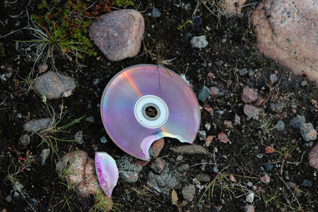 Broken compact disc on the ground close-upの写真素材