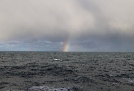 Rainbow over the sea, stormy sky and raincloudsの写真素材