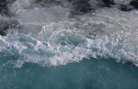 Close up of blue sea water with white foam and waves. Natural background