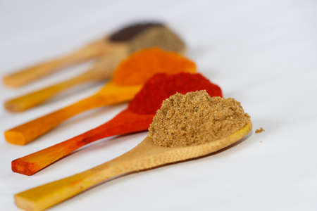 Kerala Style Curry Ingredients In Wooden Spoon. Chili Powder, Coriander Powder, Turmeric Powder In White Background. Selective Focus On Coriander Powderの写真素材