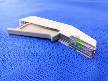 Closeup Image Of White Color Disposable Surgical Skin Stapler In Blue Background. Selective Focus