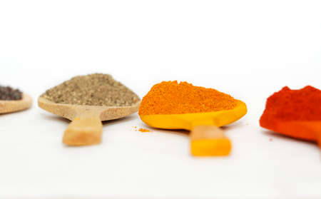Indian Curry Powders In Isolated Wooden Spoon. Selective Focus On Turmeric Powder