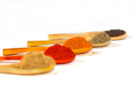 Indian Curry Powders In Isolated Wooden Spoon. Selective Focus On Turmeric Powder