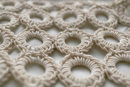 Close-up of braided cord pattern rings on white textured background. Selective focus.