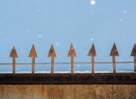 Close-up part of the concrete wall with a vertical metal shafts and snowfall.の写真素材