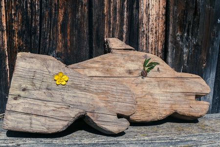 Retro image. Two old wooden carved horse's heads (children's toy - horse head on stick) are laying on old shabby bench on old wooden background.の写真素材