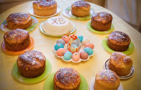 Easter cuisine. Easter cakes, curd Easter and dyed eggs stand on covered yellow tablecloth table.の写真素材